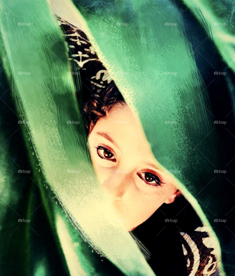 Eyes behind green leaves