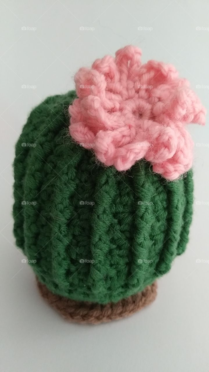 a small crocheted cactus with a pink blossom