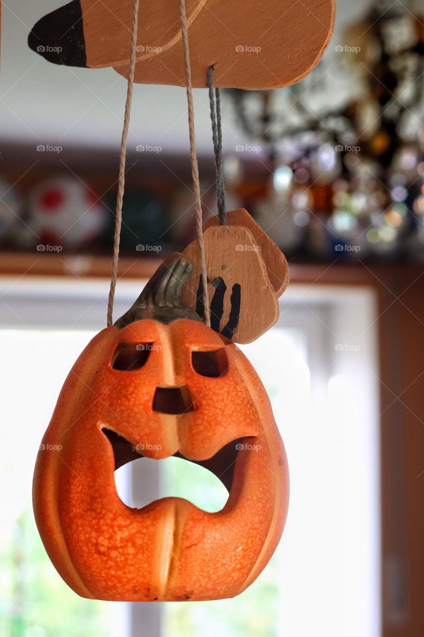 Hanging orange Halloween pumpkin in front of a window and glittering chandelier