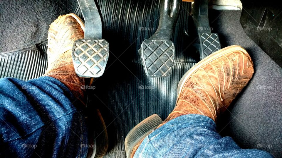 Dirigindo, pés nos pedais; embreagem, freio e acelerador.