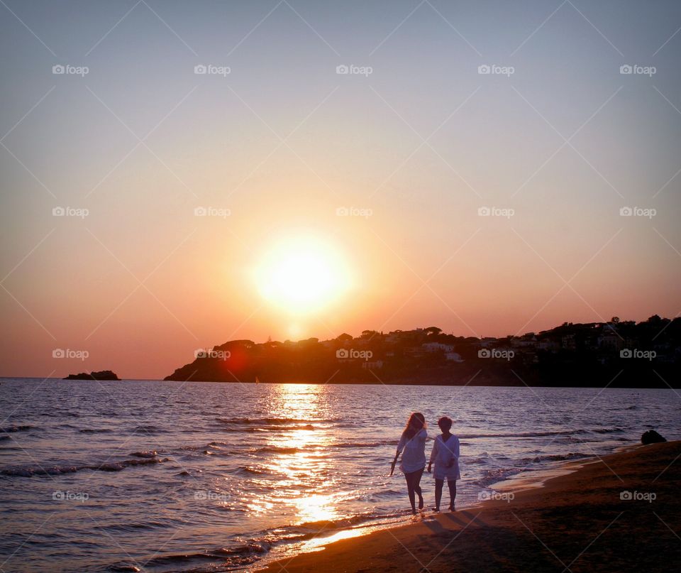 Two girls walking on beach in a warm October.