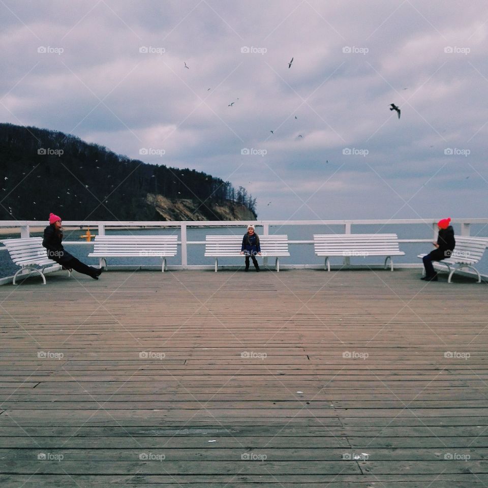 People relaxing on bench near sea