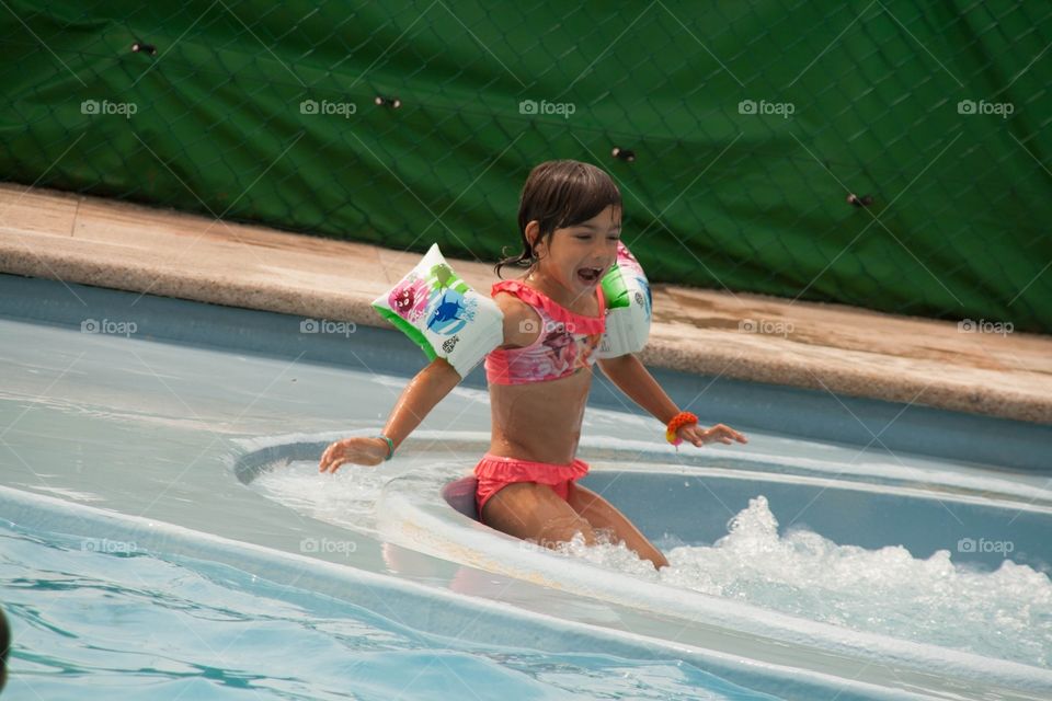 Little girl sitting on the side of a bubble bath 