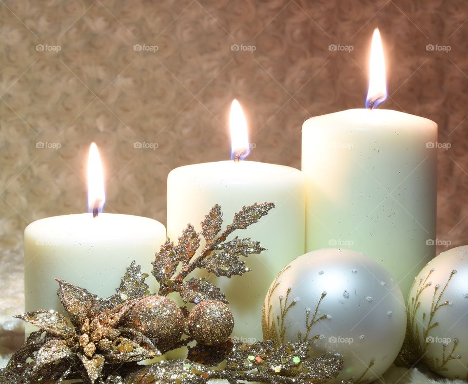 Ivory candles burning with golden Christmas decorations as accessories 