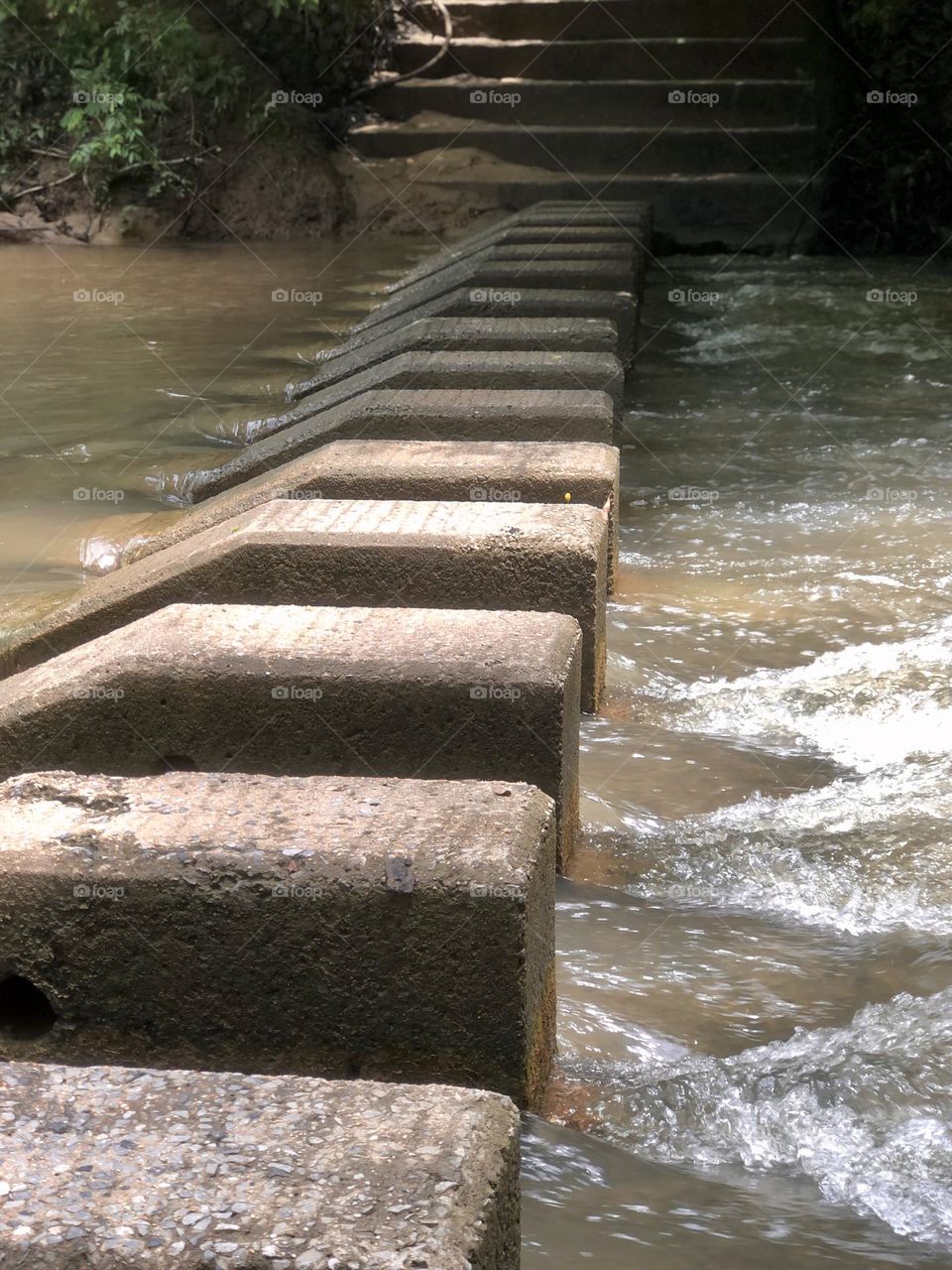 Concrete footers create an elevated river crossing. The steps are still visible as the muddy waters rush by.