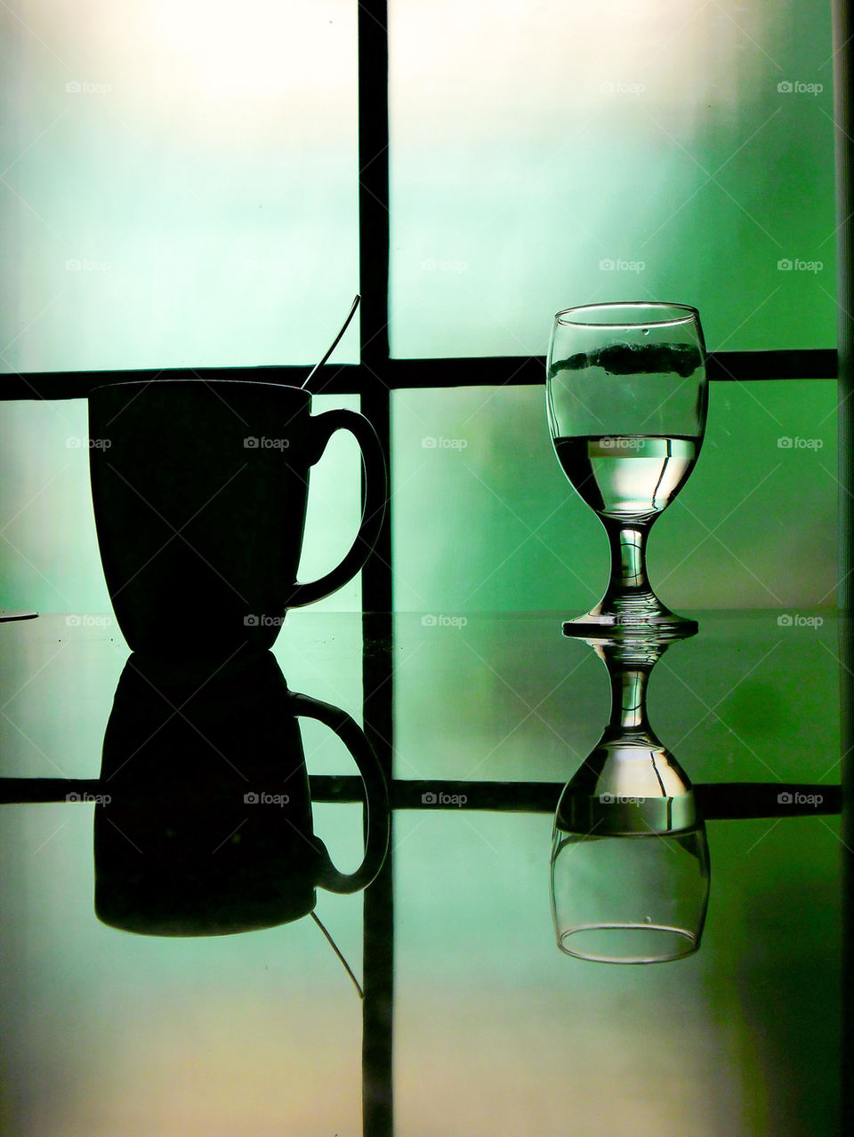 water goblet and coffee mug on a reflective table
