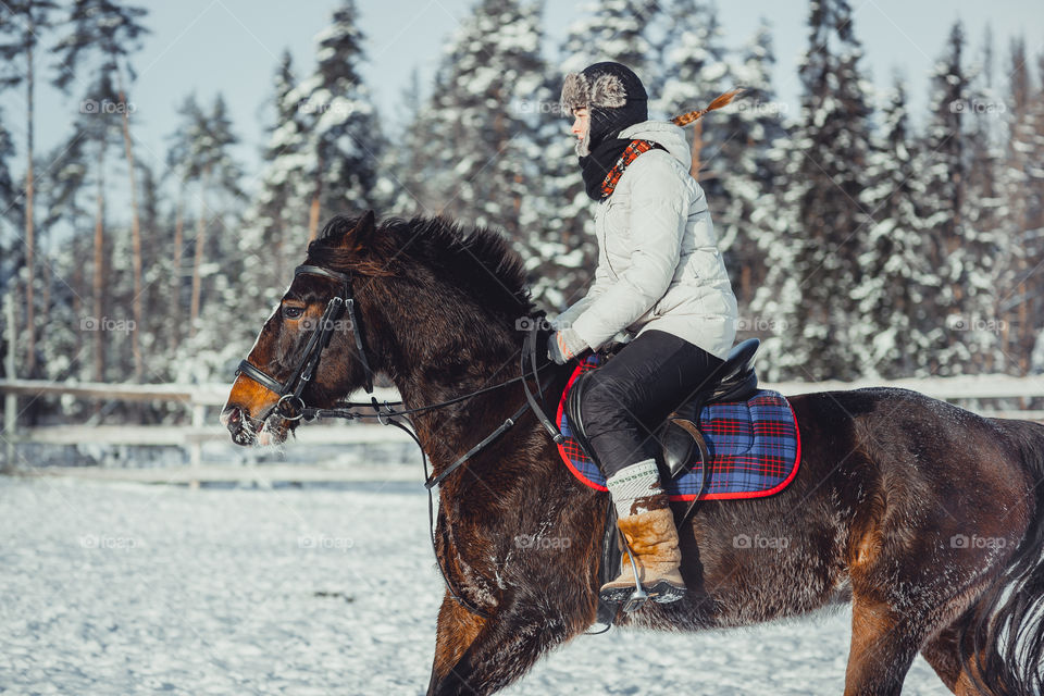 Teenage girl horseback jumping at cold winter day