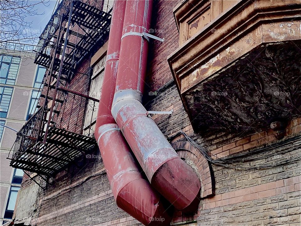 An eclectic old brownstone on “Waverly St” in “Clinton Hill”, Bklyn with metal fire escapes and old style architectural detail such as rounded windows, ornaments and stucco and a brick facade. 2023. Hypnotic Productions