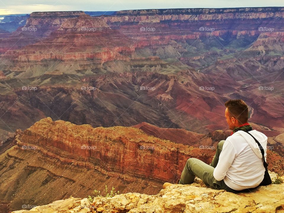 Rear of man sitting on rock