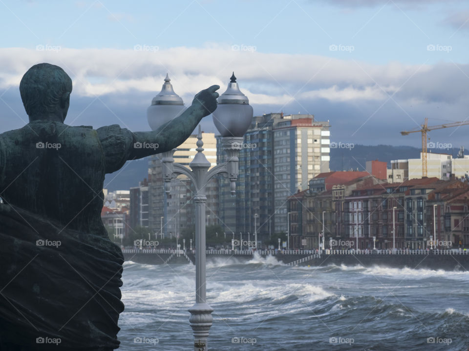 The emperor is pointing at the city of Gijon in an stormy day of summer in Asturias