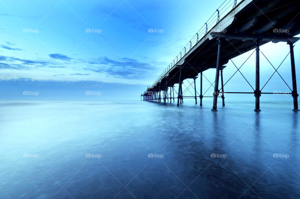 Long exposure shot of a pier with seemingly frozen sea against a light
