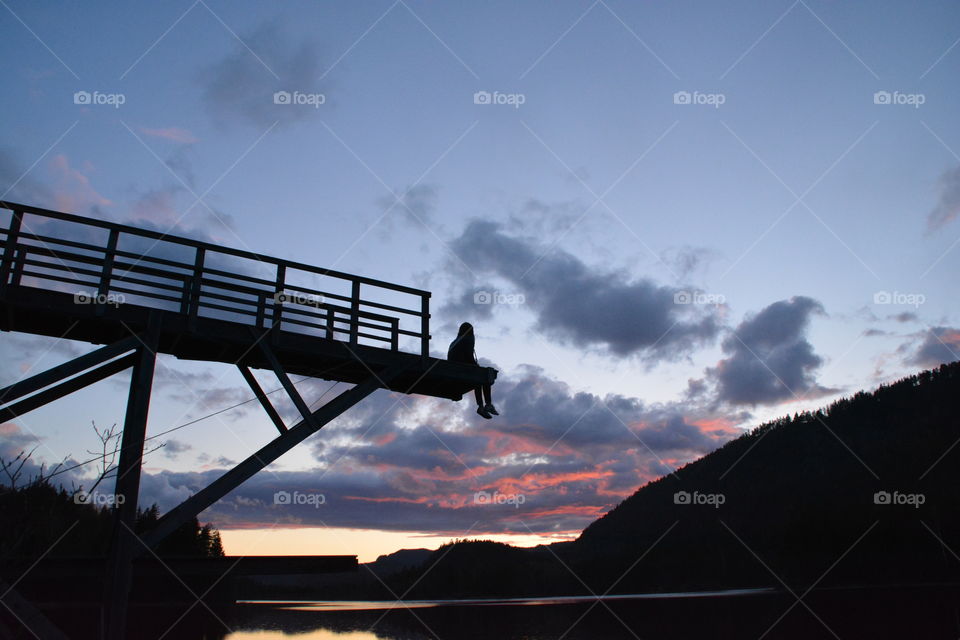 Silhouette of girl sitting on pier