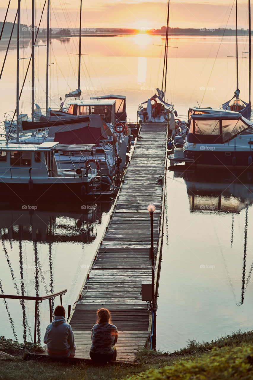 Yachts and boats moored in a harbour at sunrise. Candid people, real moments, authentic situations