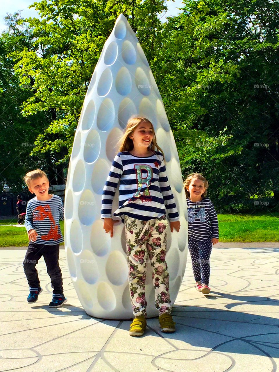 Children standing near white sculpture in park