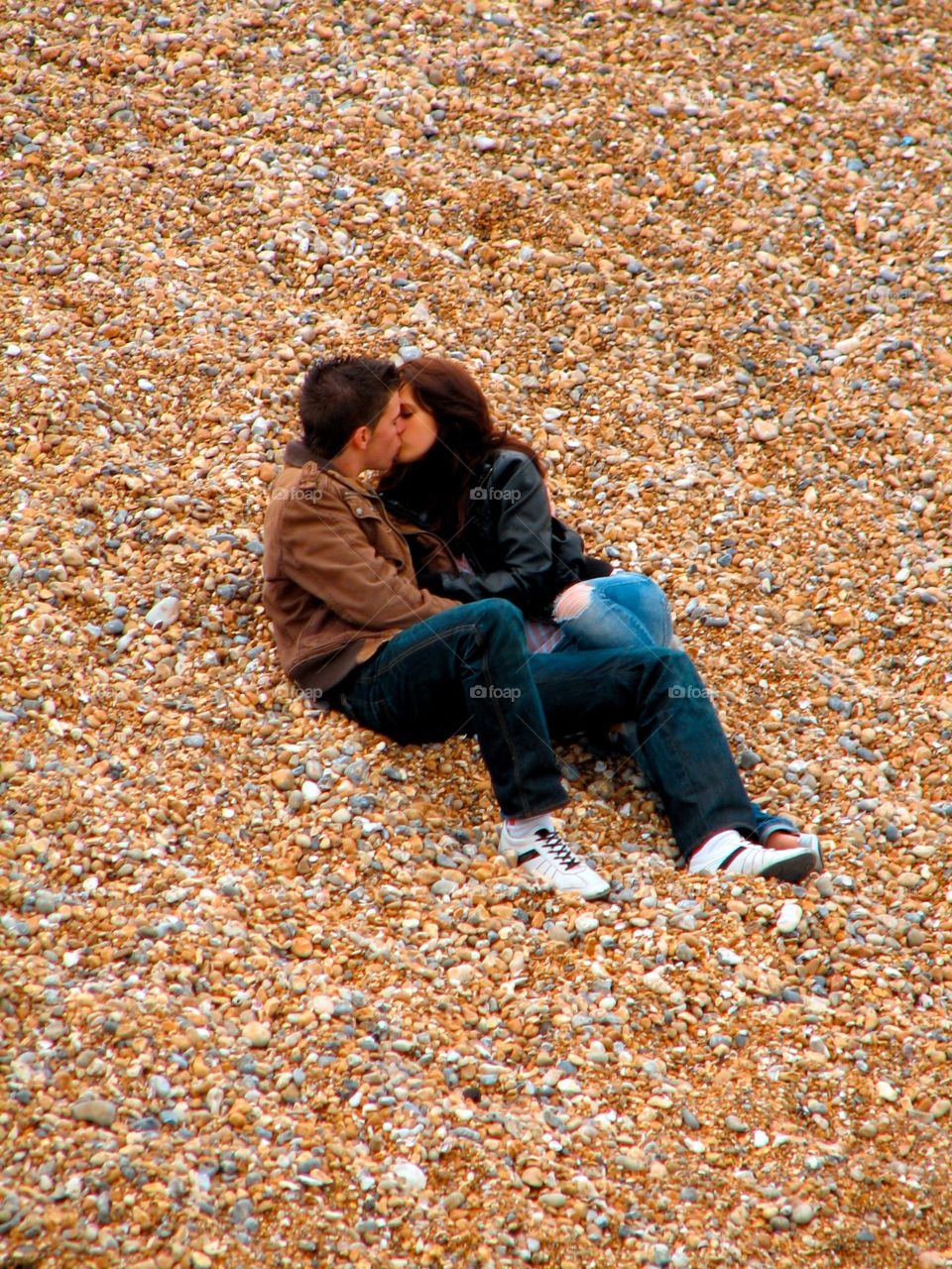 Love on the rocks. A couple kissing on the beach in Brighton, England