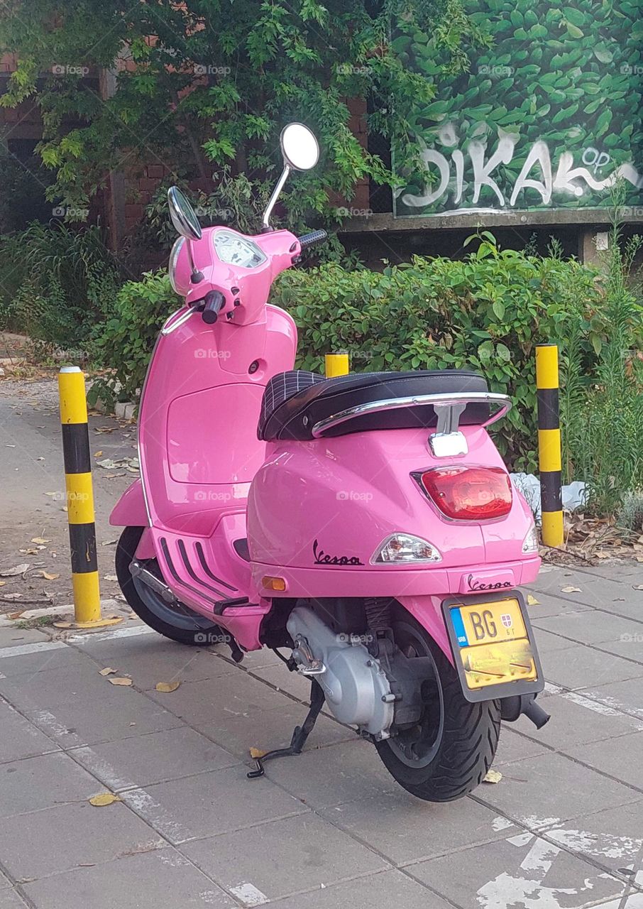 Pink scooter parked on the street.  Barbie style