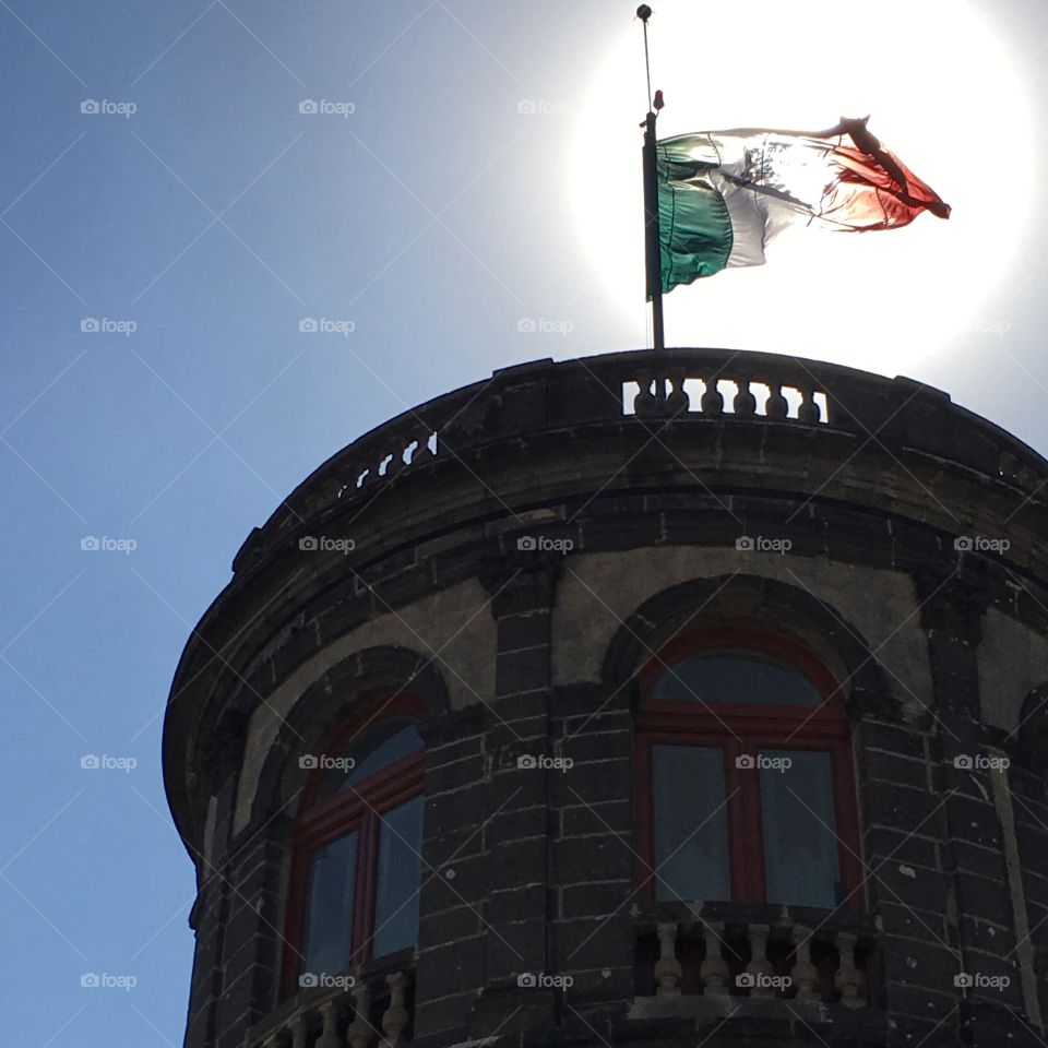 Mexican flag on castle against the sun 