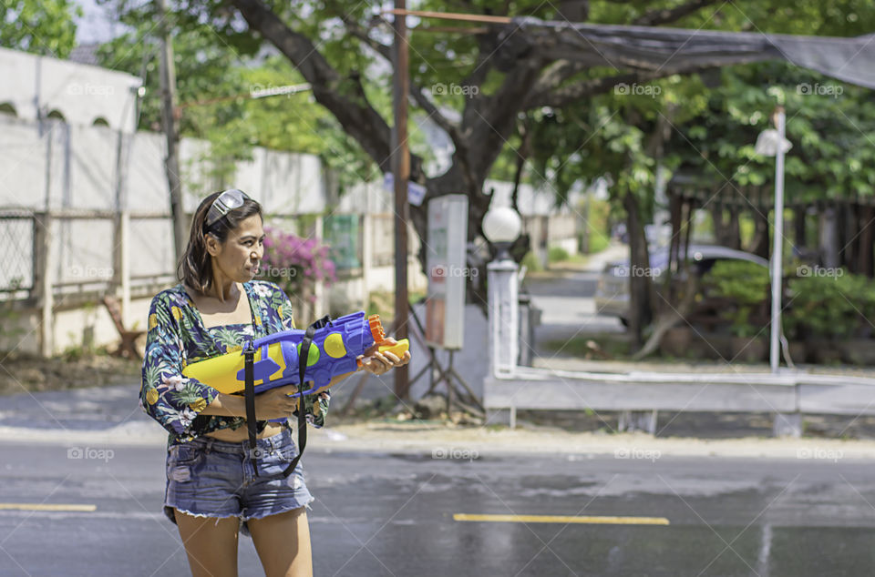 Asian woman holding a water gun play Songkran festival or Thai new year in Thailand.