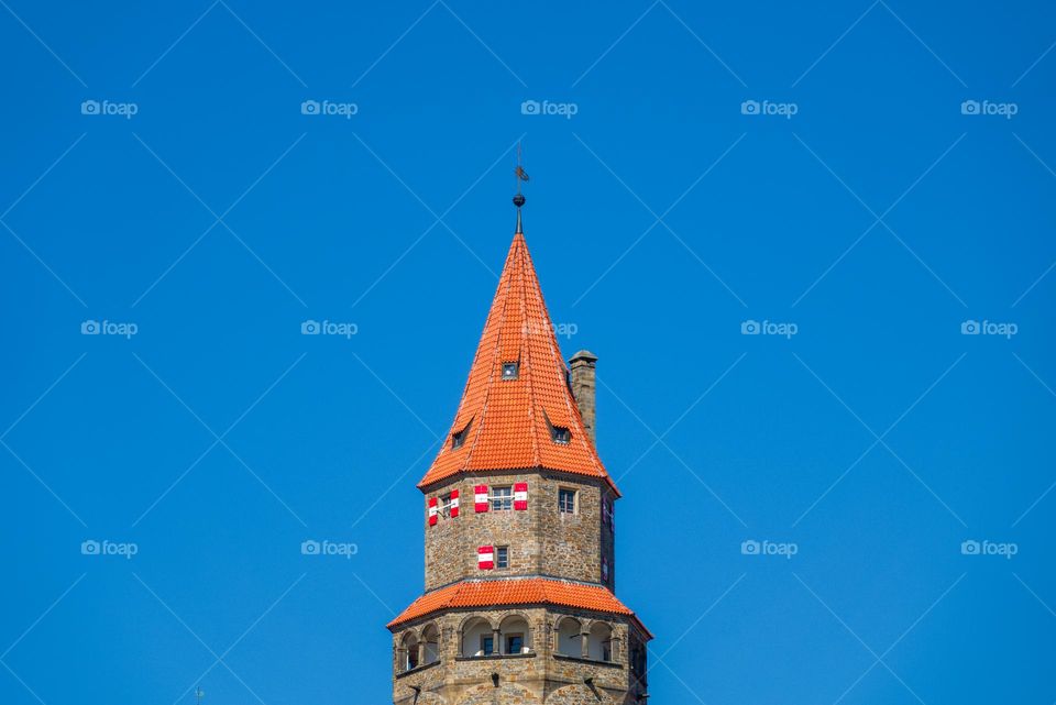 Detail of the tower of the famous Czech castle Bouzov with a typical roof and shutters and clear blue sky.