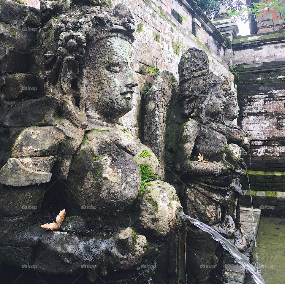 Ancient stone female figures pour water for worshippers to bathe in at Bali’s Elephant Cave Temple.