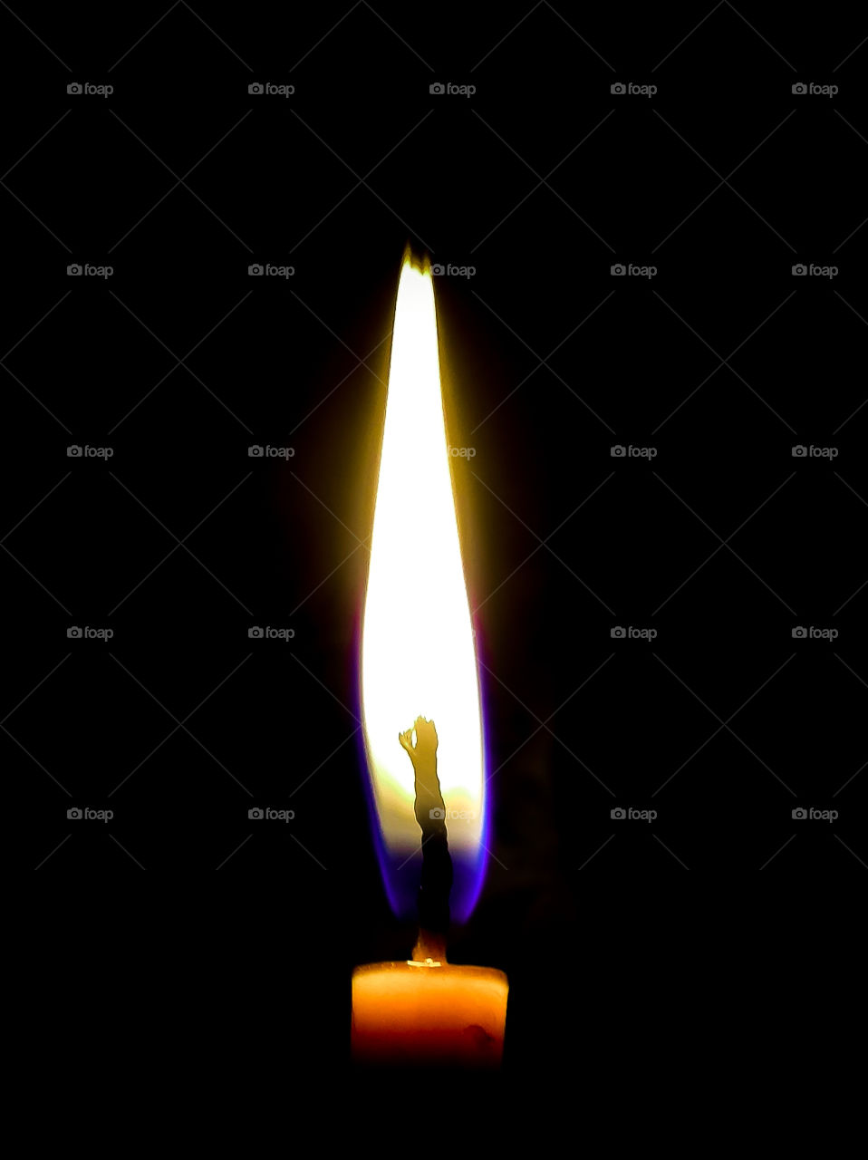 A burning candle on a black background in a frame
