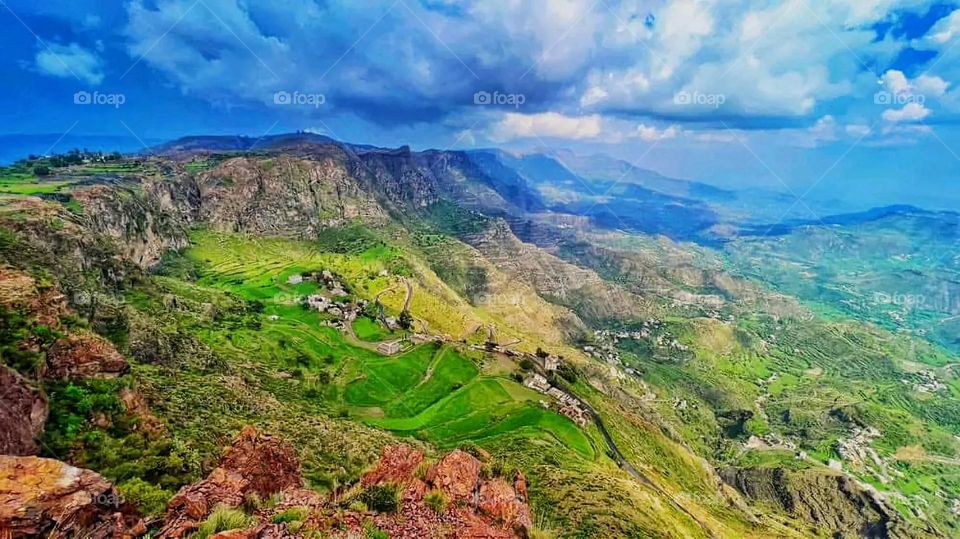 The image embodies a natural natural plate of the mountains of nature, where green agricultural stands are graded on the slopes as if they were lines of a poem, which fog harmoniously wrapped, and clouds hugged them in the mountain knife and the whis