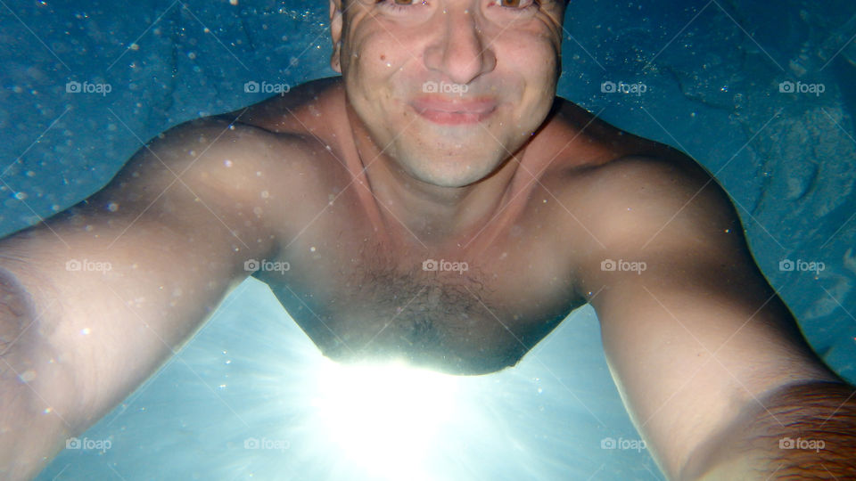 Man diving, man underwater smiling and relaxing in big blue sea with his camera