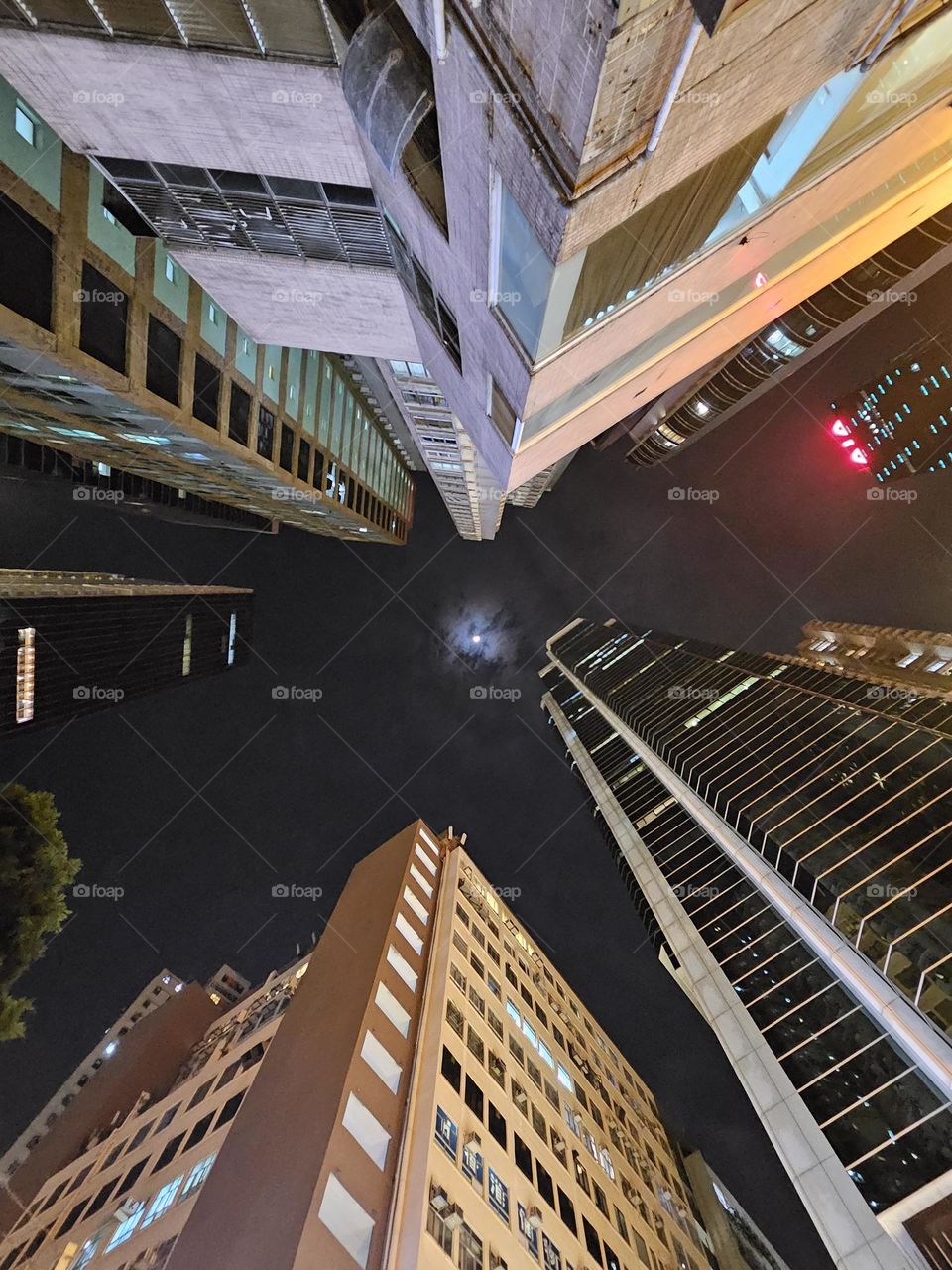 looking up at the sky the moon surrounded by tall buildings at Tin Hau Hong Kong