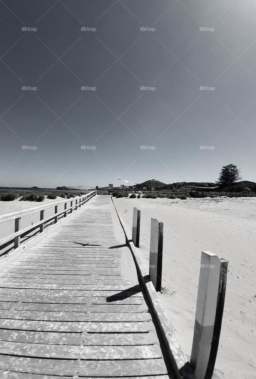 the walkway of a beach, endured in black and white with only a touch of its colours left.