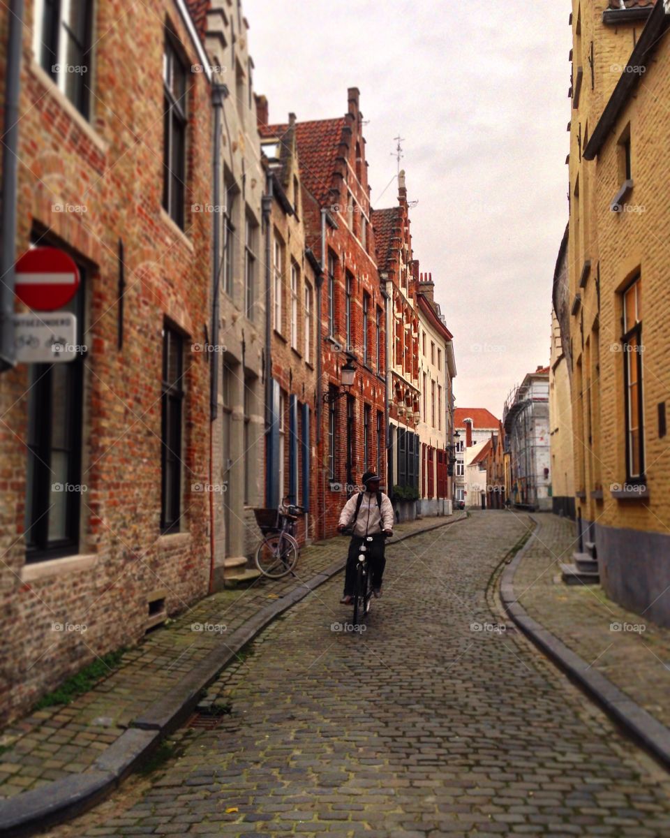 A Rider in Brugge. A local rides through winding homes and on the cobblestone streets of Brugge, Brussels. 