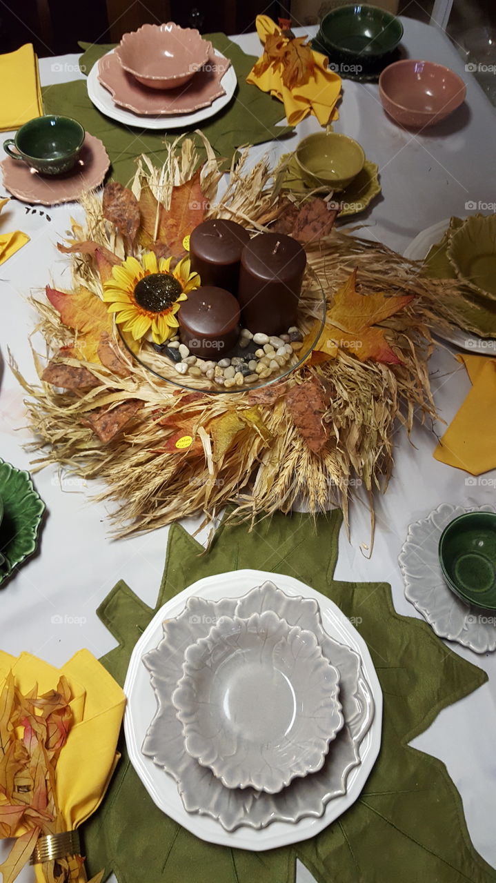 Autumn tablescape with candles, linens, and leaf plates.