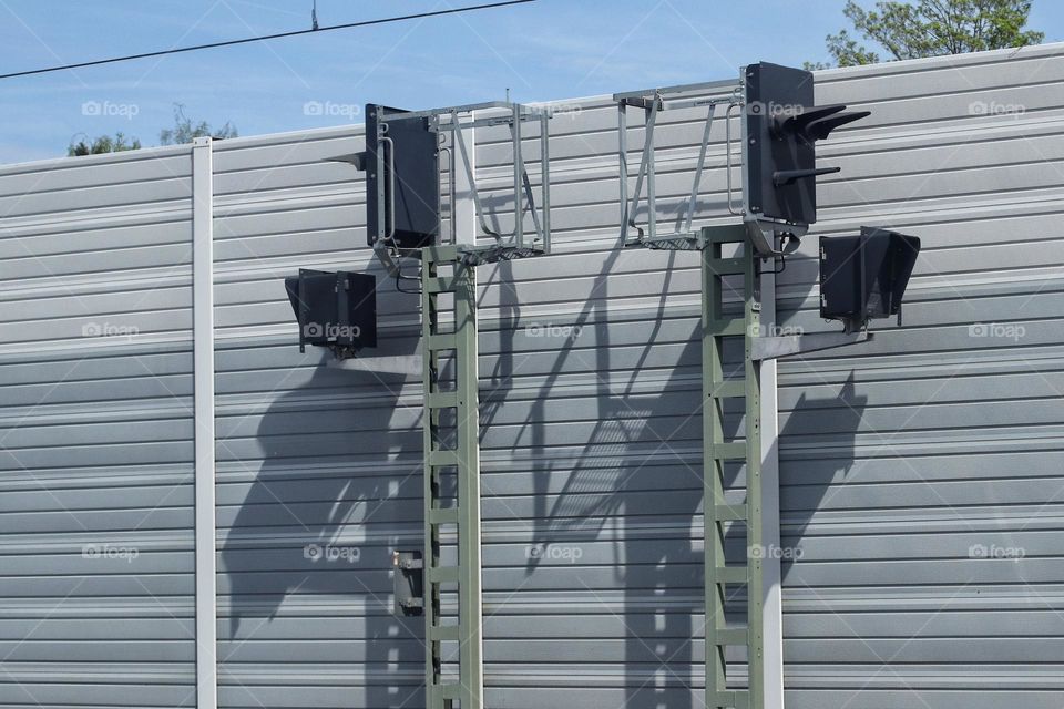 Two railway signals in front of a noise barrier in the sunlight