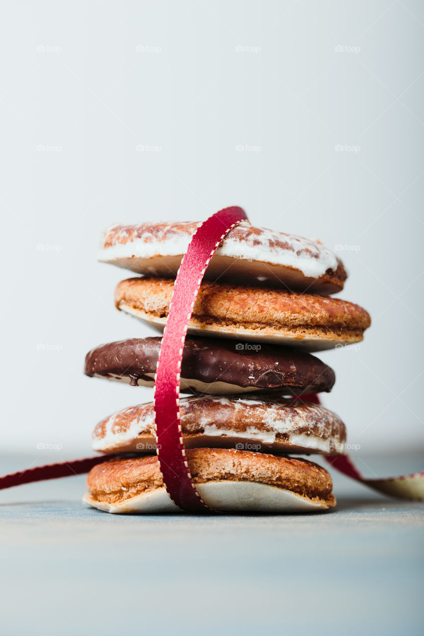 A few gingerbread cookies wrapped in red ribbon Happy Christmas on wooden table. Plain background. Portrait orientation