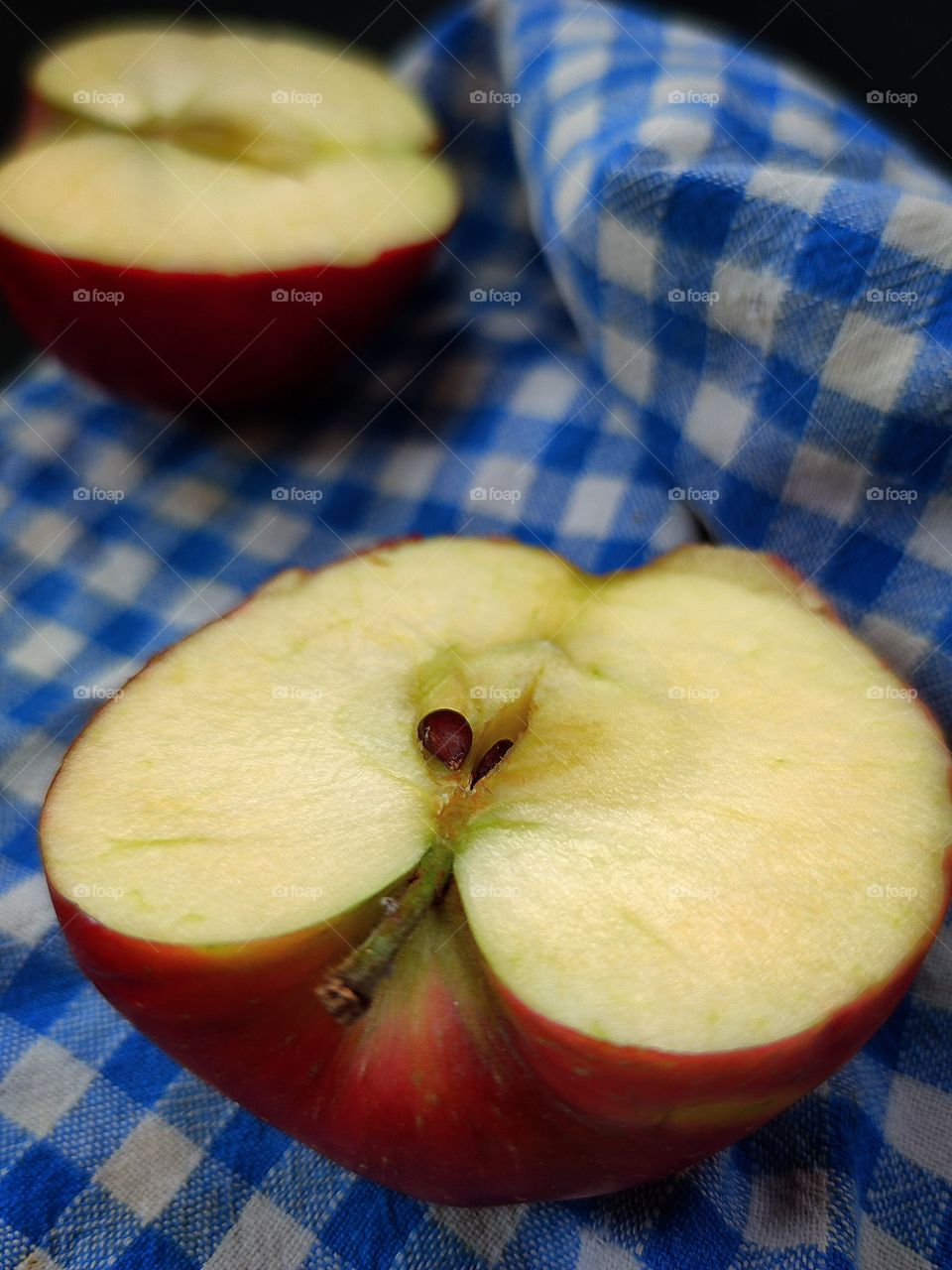two halves of an apple on a towel in a blue cage