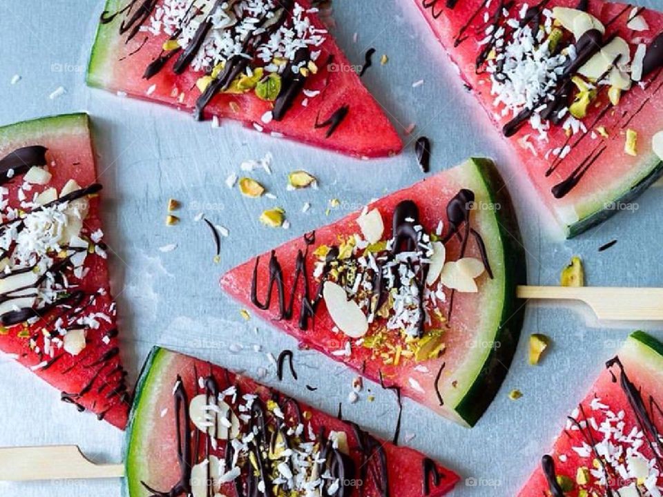 Watermelon desserts with nuts, coconut and drizzled chocolate. 