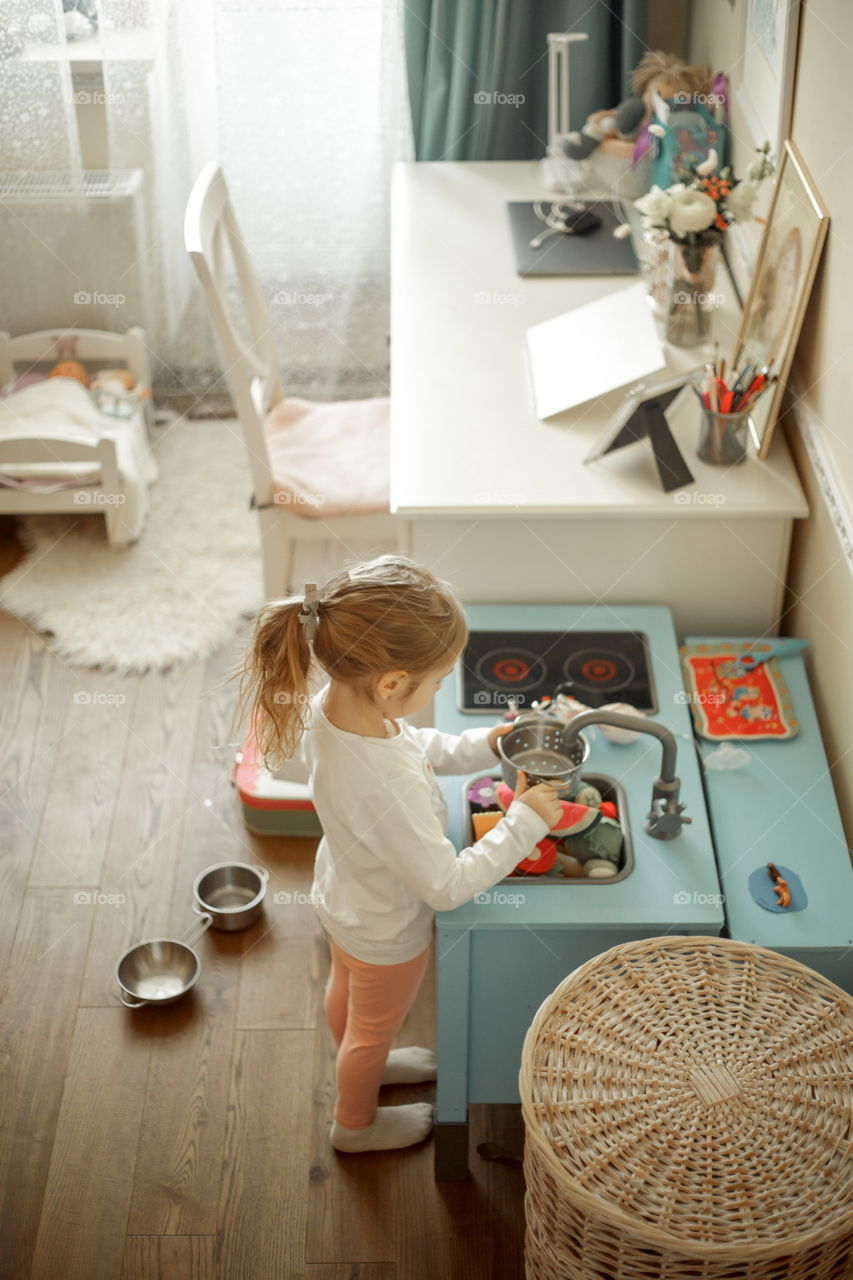 Little girl playing with Ikea kitchen in playroom 