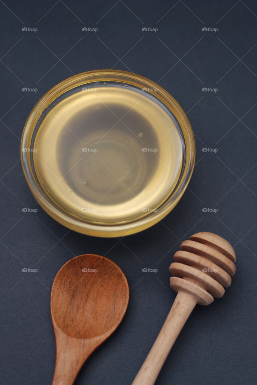 Honey in bowl with spoon. Black background. Top view.