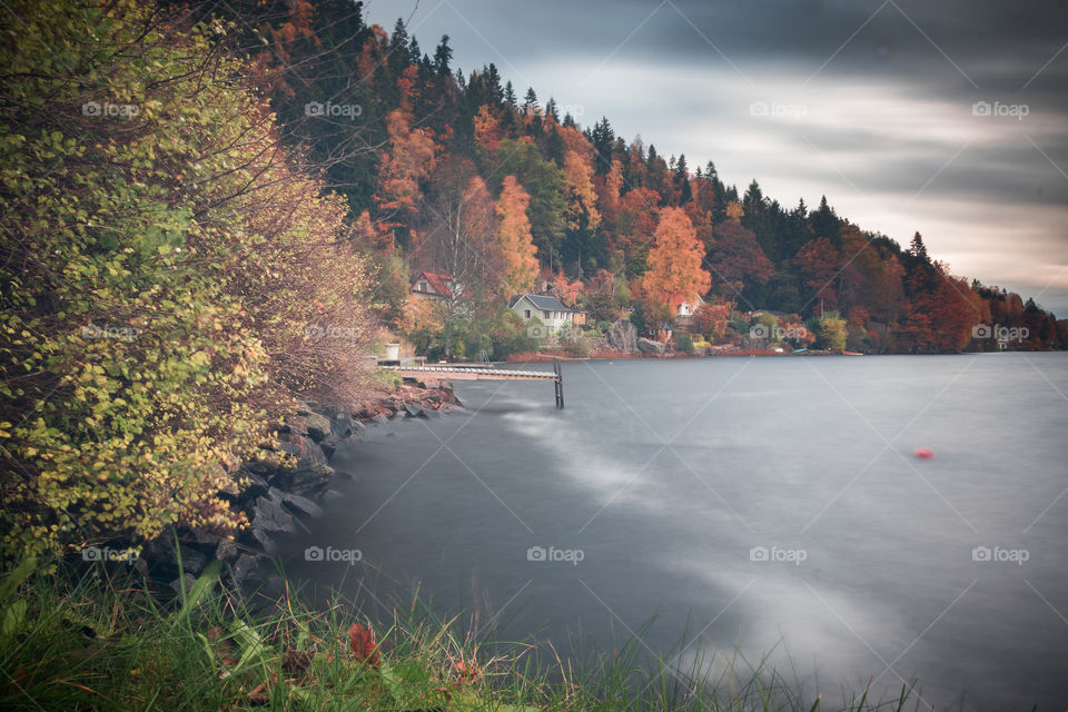 autumn foliage along the shoreline, spotted with tiny cottages in the Swedish countryside