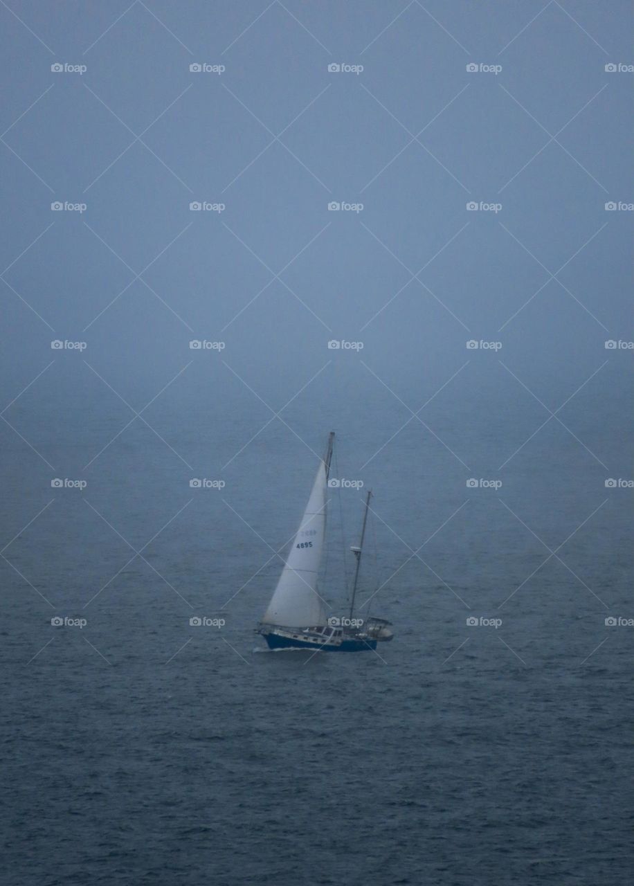 Boat sailing on the ocean on a foggy day.