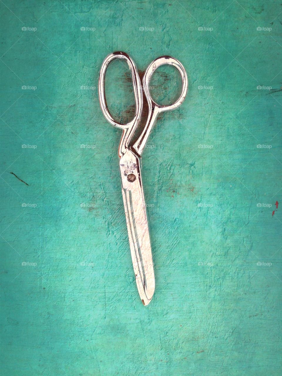 A pair of Scissors . A pair of scissors on a coloured wooden background 