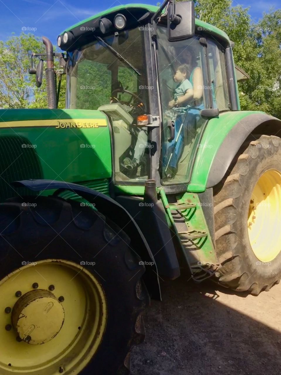 Toddler and Mum having a ride in a real green John Deer tractor. Beautiful sunny day on the heart of Kent 