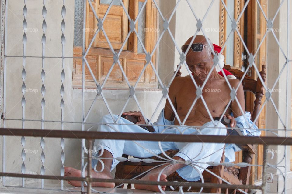Cuban People.Elderly man naps on front porch.