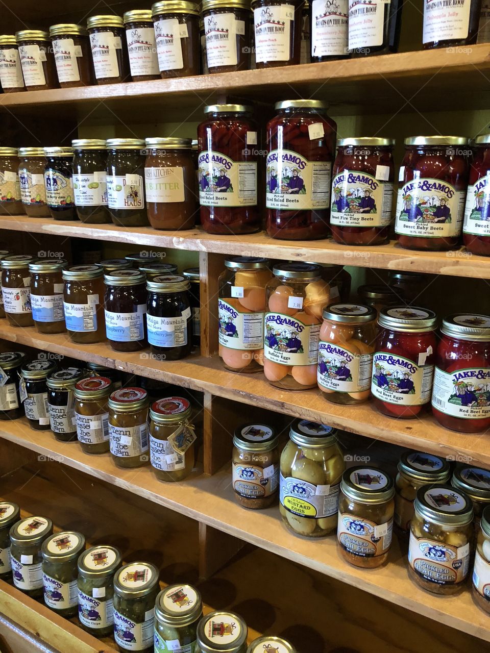Many jars filled with preserves on shelves in an old store. 