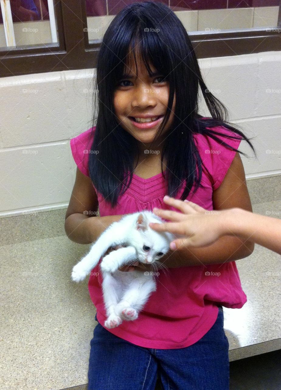 Can we take her home? Girl holding tiny white kitten 