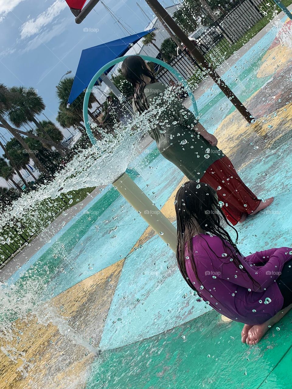 Children having lots of fun in the water at the colorful kids splash pad at the city park for children during a really warm day in Florida.