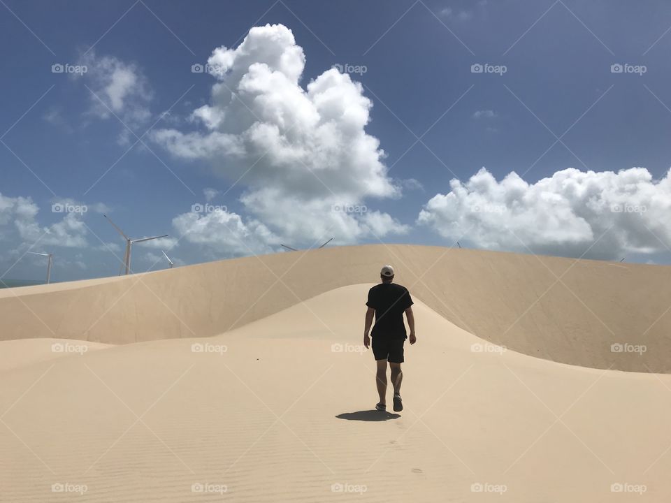 Man walking over sand dunes Ceará Brazil