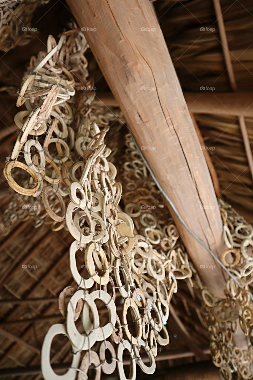 wooden circular shaped disks used as a fishing net hanging on a wood beam