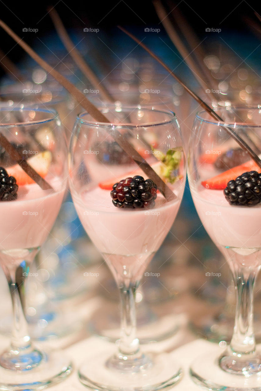 Rows on individual desserts topped with fresh fruit and a stick of chocolate