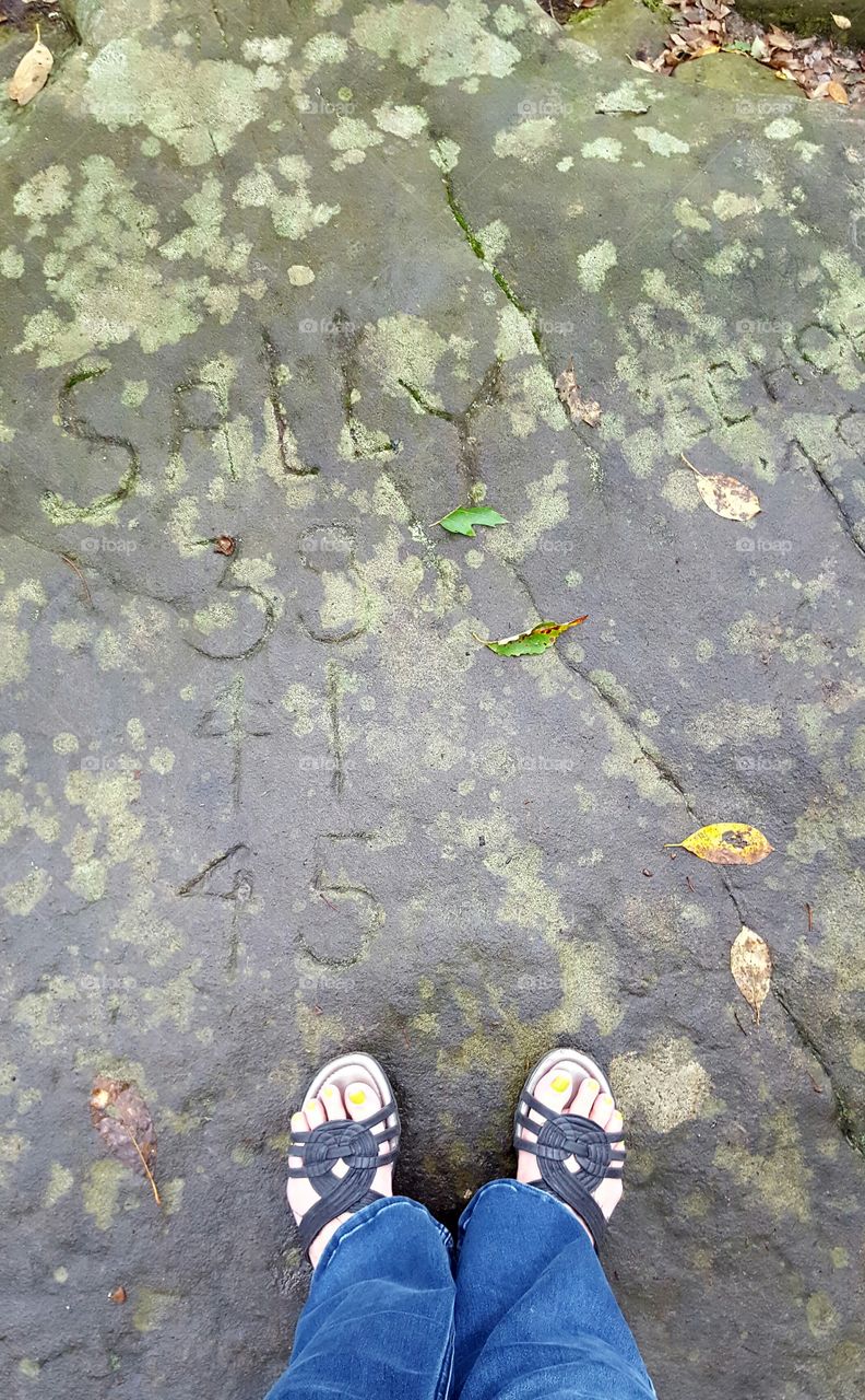 Couple has carved their names in a boulder with all the years they visited this forest location.