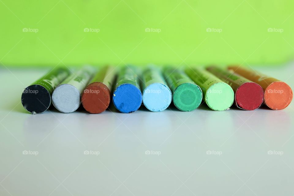 Colored crayons lined up on the green background